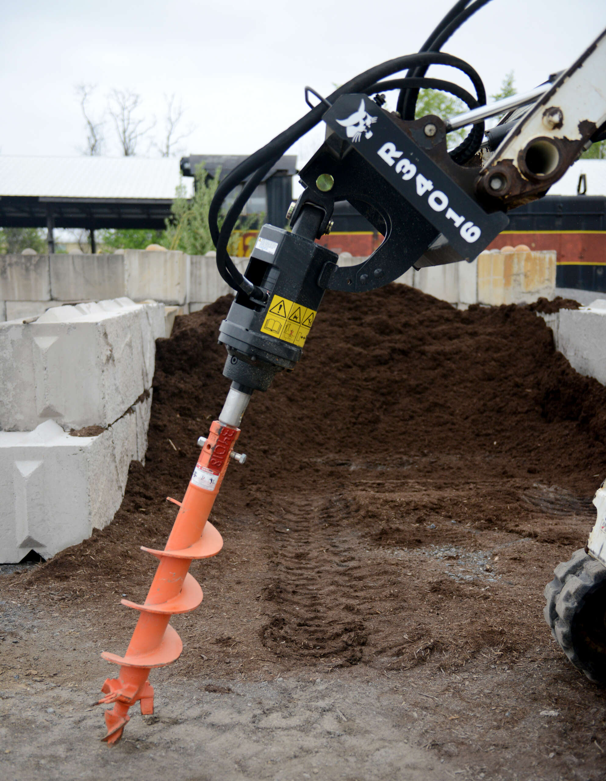 Bobcat Auger Attachment in front of a pile of mulch